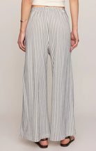 Person wearing black and white striped wide-leg pants on a plain background