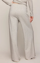 A person shown from the back wearing light heather gray wide-leg sweatpants and a matching long-sleeve top against a plain beige studio background.