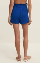 Blue shorts worn by a person on a beige background