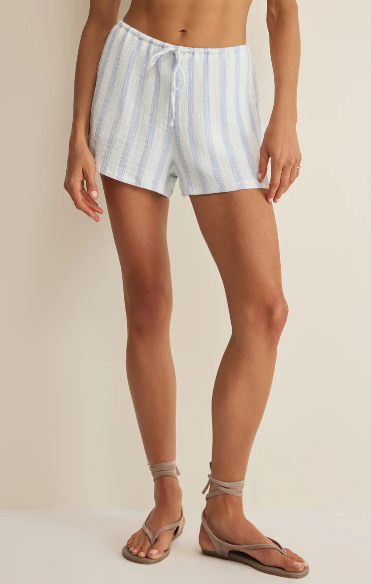 Person wearing light blue and white striped shorts on a beige background