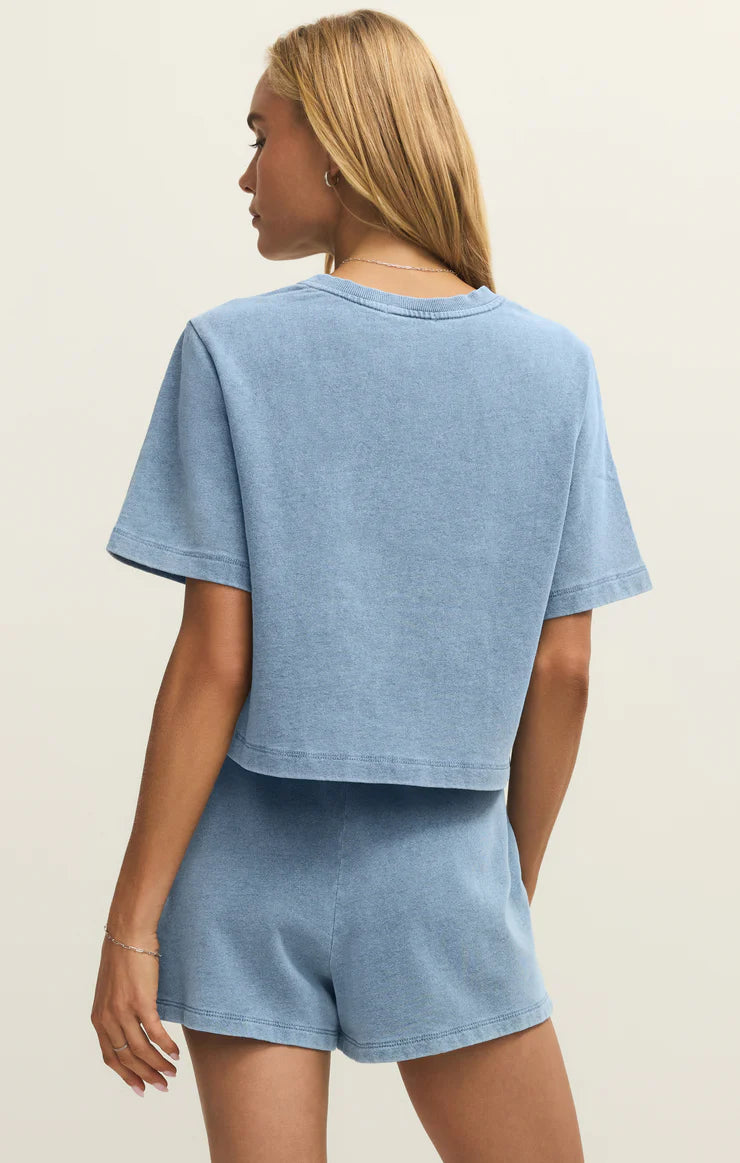 Person wearing a blue t-shirt and shorts set on a beige background