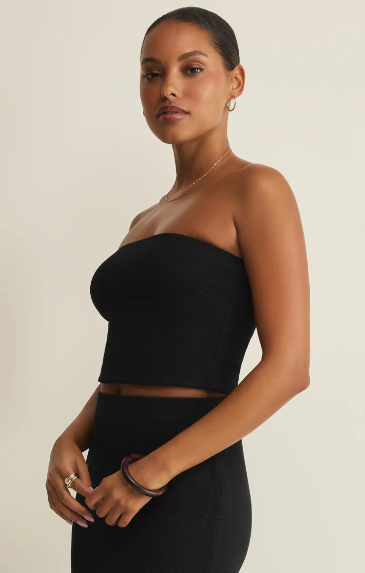 Woman wearing a black strapless top and skirt on a beige background