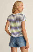 Woman wearing a striped shirt and denim shorts on a beige background