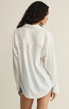 Woman wearing a white button-up shirt against a beige background