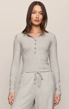 Model wearing a heather gray long sleeve henley top with button-front detail.