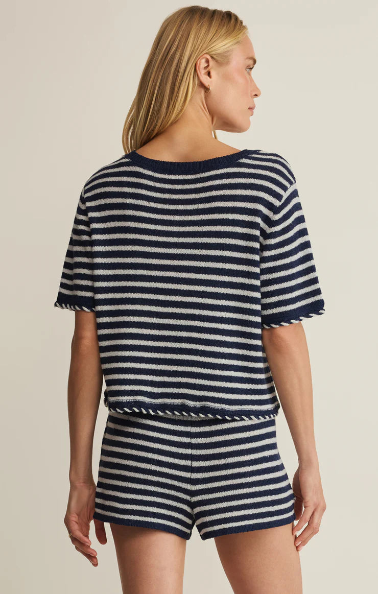 Woman wearing a navy and white striped outfit on a beige background
