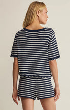 Woman wearing a navy and white striped outfit on a beige background