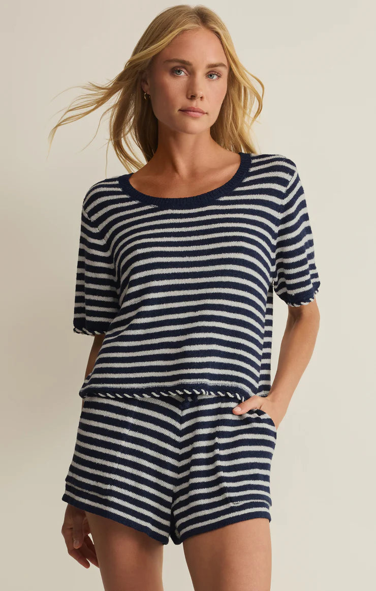 Woman wearing a navy and white striped outfit on a beige background