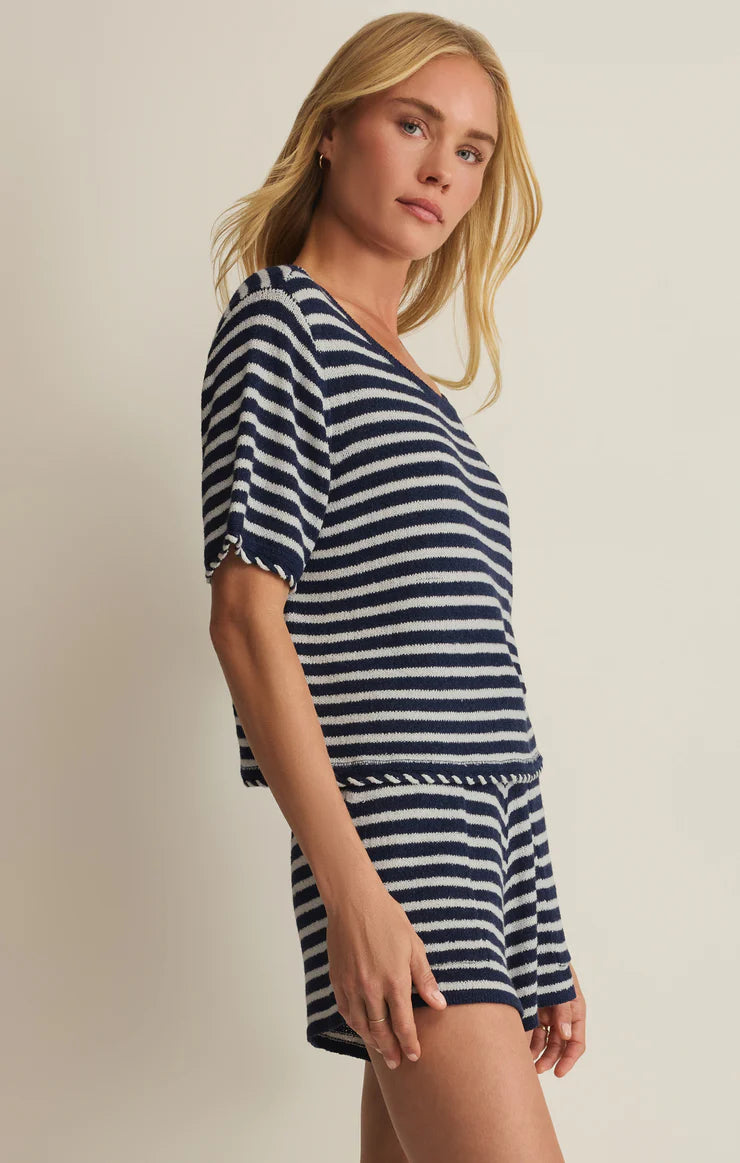 Woman wearing a navy and white striped dress against a plain background