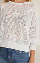 White mesh sweater with star patterns worn by a person, against a neutral background