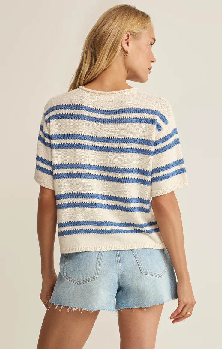 Woman wearing a striped sweater and denim shorts on a plain background
