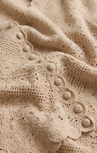 Close-up of beige knitted fabric with a textured pattern