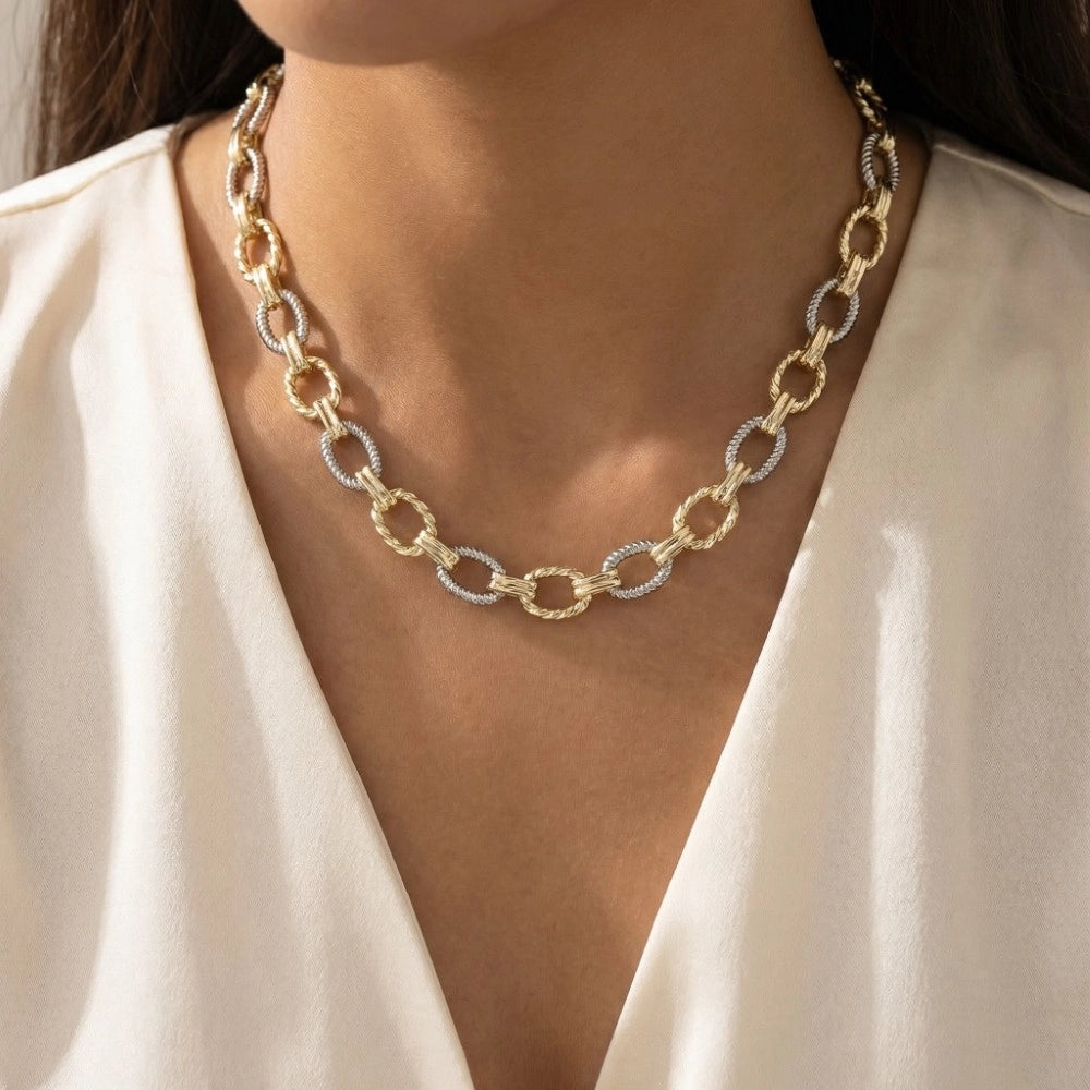 Gold chain necklace worn by a person against a neutral background