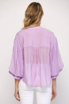 Person wearing a light purple blouse with a white background