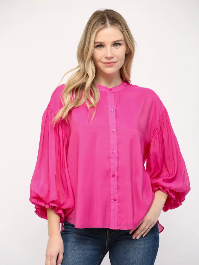 Woman wearing a bright pink blouse with puffed sleeves on a white background