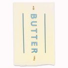 A cream-colored paper butter wrapper or label with blue text reading 'BUTTER' and small gold text reading '4 oz' and '116 g', shown on a plain white background.