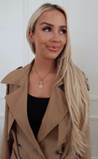 Woman wearing a beige trench coat with a white background