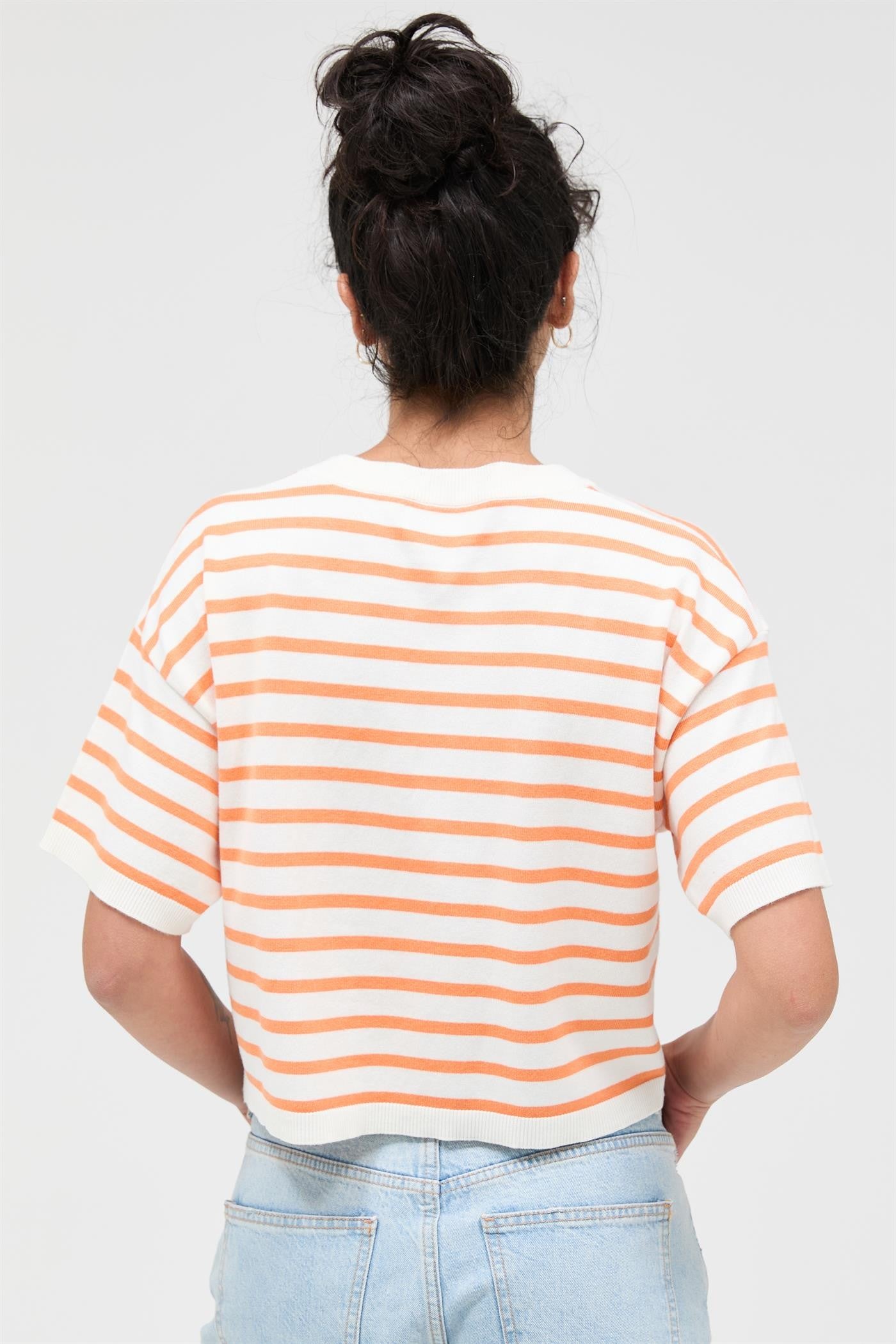 Person wearing a striped shirt and light blue jeans on a plain background