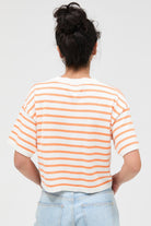 Person wearing a striped shirt and light blue jeans on a plain background