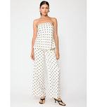 Woman wearing a strapless polka dot top and wide-leg pants on a white background