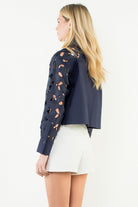 Woman wearing a navy blue jacket with cut-out designs on a white background