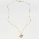 A delicate gold chain necklace with a small rectangular pendant featuring a passport cover