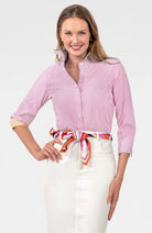 Woman wearing a pink striped shirt with a colorful scarf around her neck on a white background