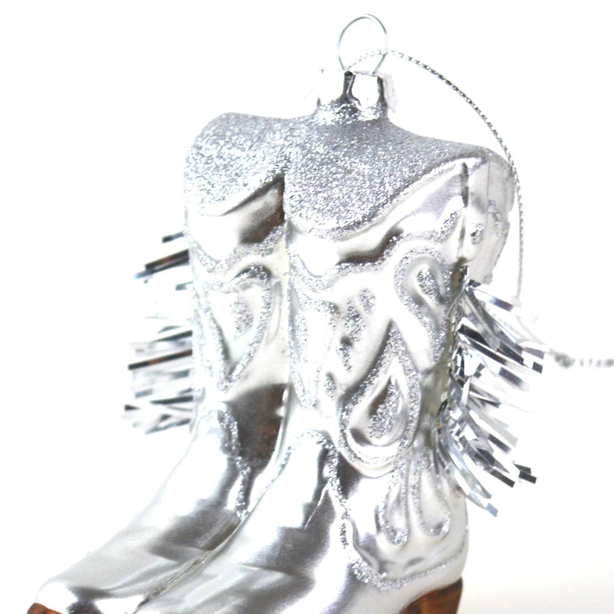 Silver cowboy boot ornament with tinsel on a white background