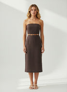 Woman wearing a strapless brown dress against a white background