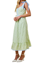 Woman wearing a green checkered dress with blue accents on a beige background