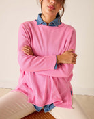 Person wearing a pink sweater with denim collar and cuffs on a neutral background