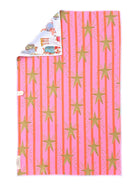 A folded kitchen towel, featuring a pink and orange vertical stripe pattern with gold starburst motifs. The underside shows a white side with a small illustrated patch and a small white tag.