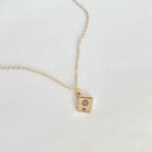 Gold necklace with a passport-shaped pendant on a light gray background