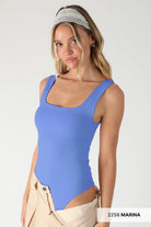 Woman wearing a blue swimsuit with beige pants on a white background