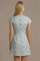 Woman wearing a floral dress against a plain background