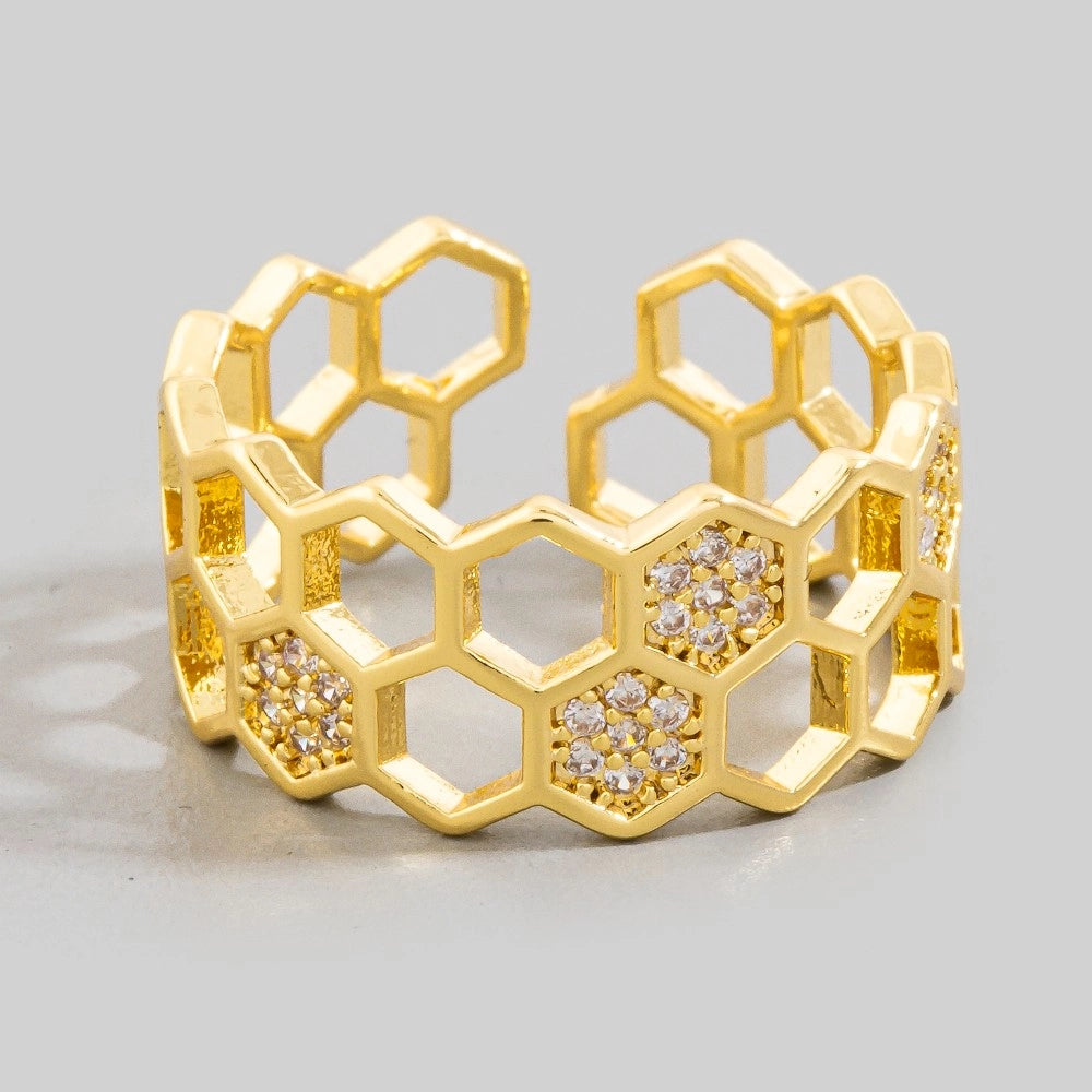 Gold honeycomb ring with embedded diamonds on a light gray background