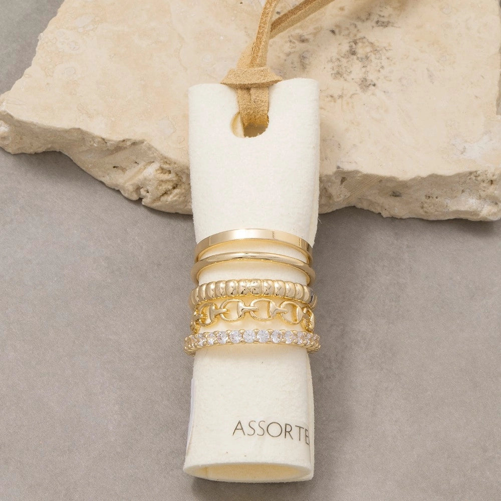 Set of gold rings in a white cylindrical holder against a stone background