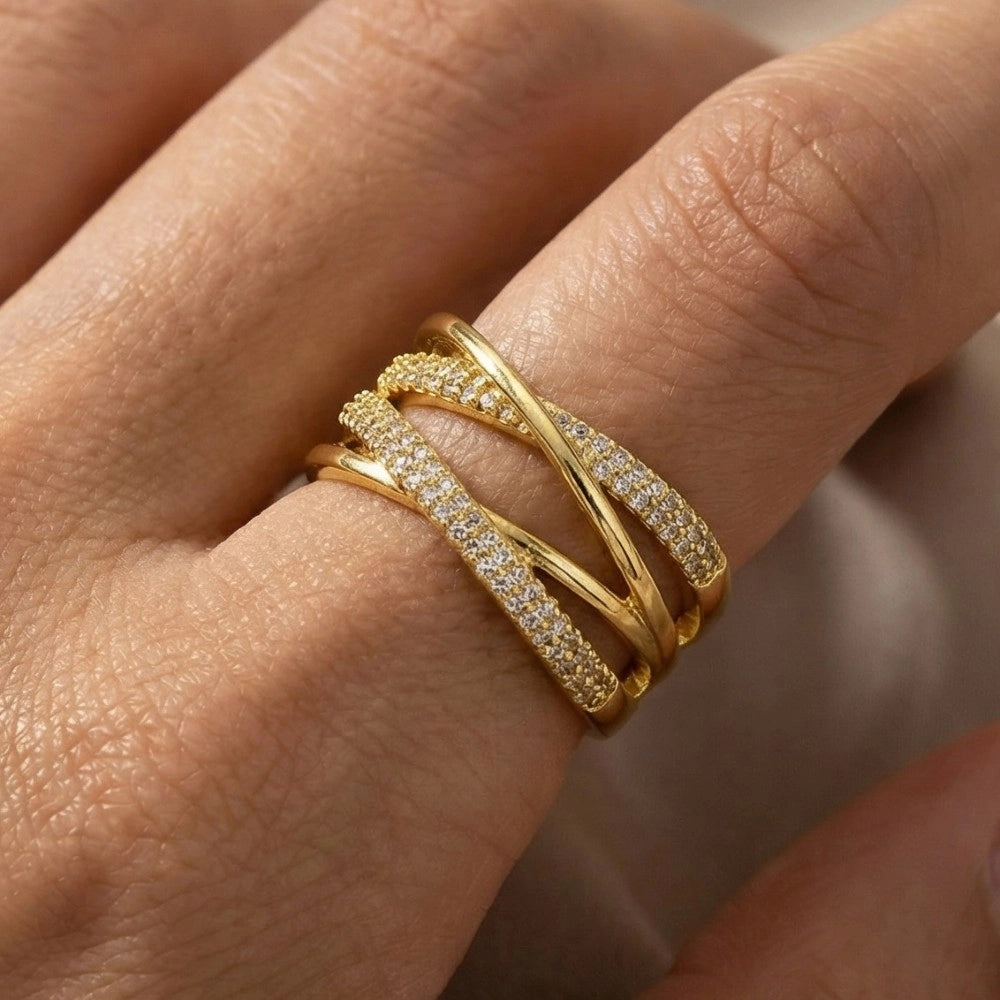 Gold ring with diamond accents on a finger against a neutral background