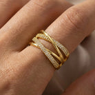 Gold ring with diamond accents on a finger against a neutral background