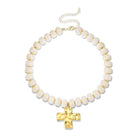 A beaded necklace featuring textured, rounded off-white beads separated by small gold spacers, with a polished gold cross pendant and an adjustable gold chain clasp, shown on a plain white background.