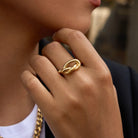 Close-up of a hand wearing a gold ring with a blurred background