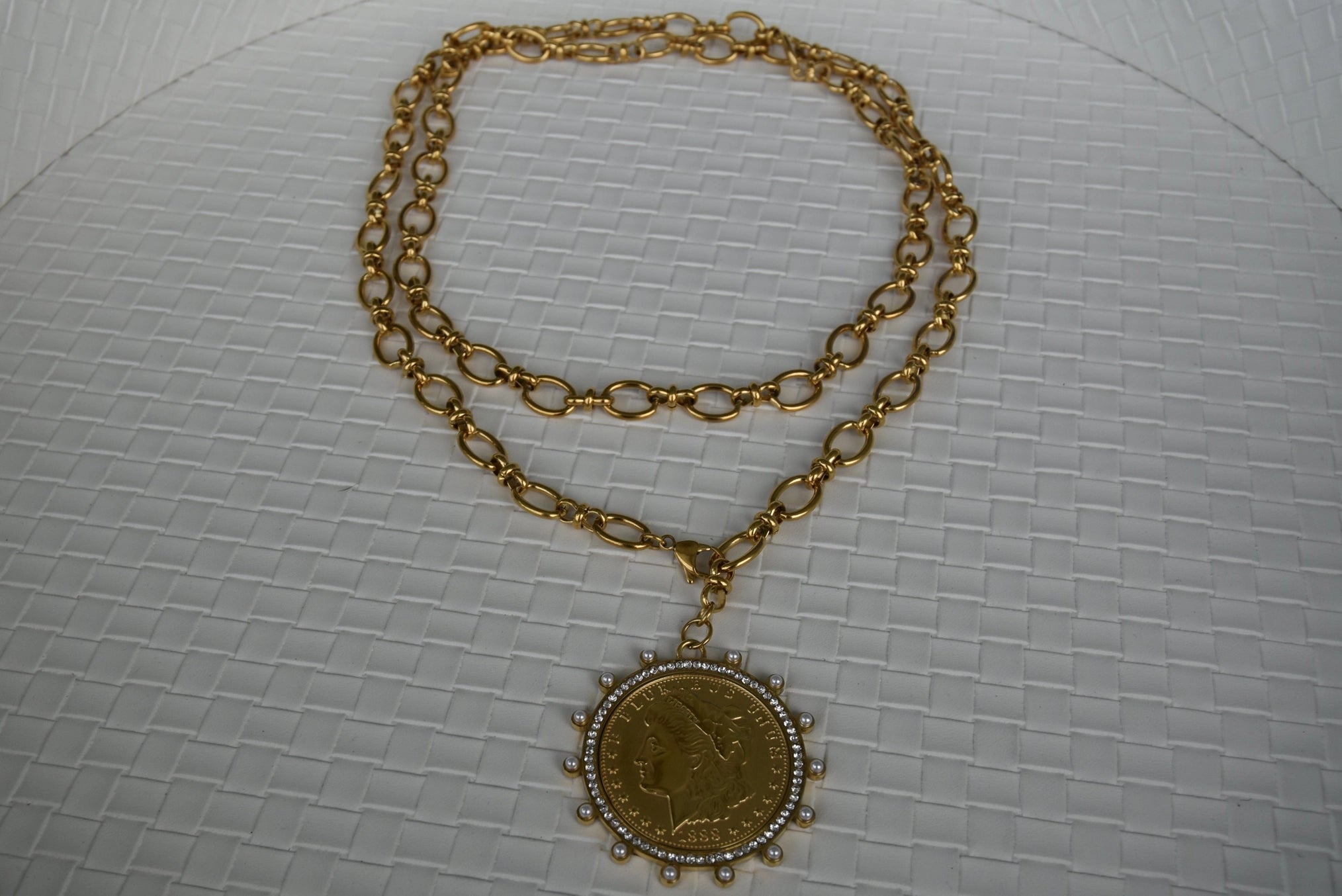 Gold chain necklace with a pendant on a textured white background