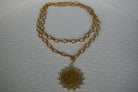 Gold chain necklace with a pendant on a textured white background