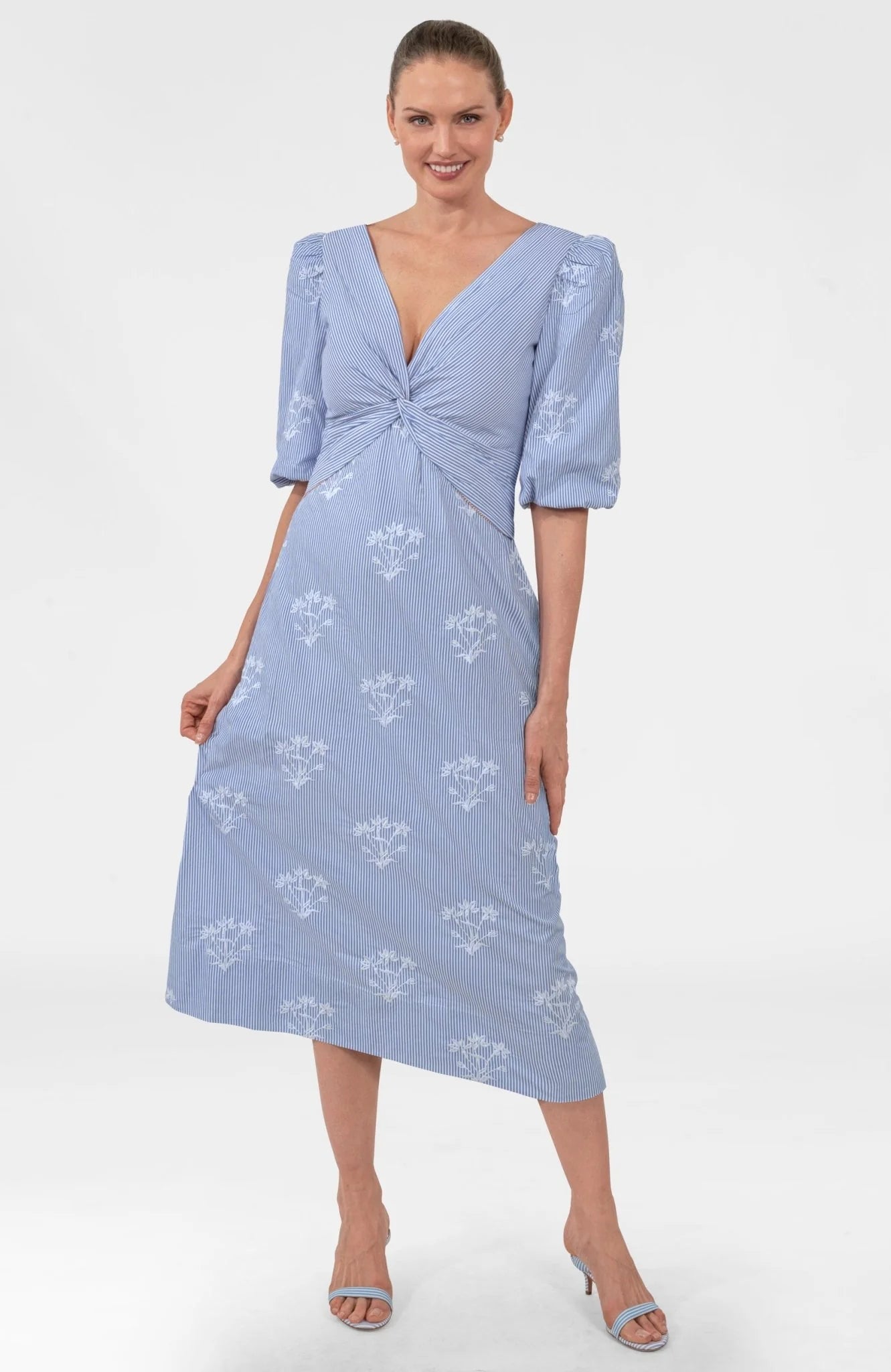Woman wearing a light blue dress with a floral pattern on a white background