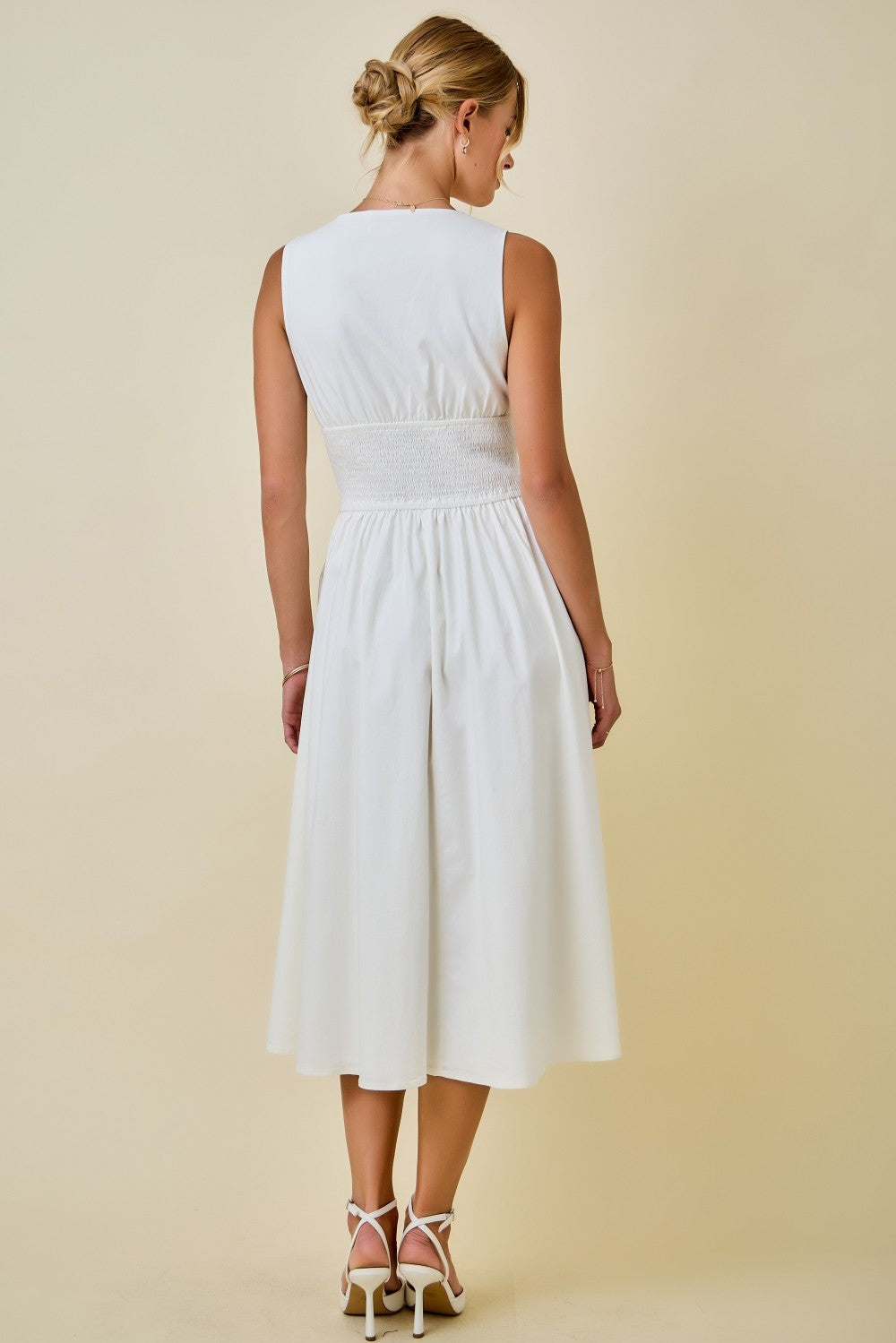 Woman wearing a white dress against a beige background