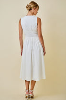 Woman wearing a white dress against a beige background