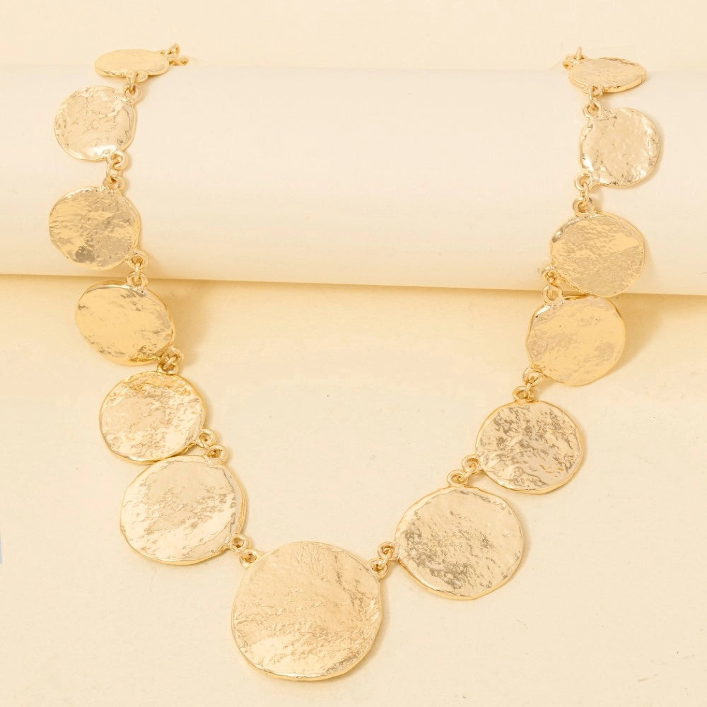 Gold necklace with round pendants on a yellow background