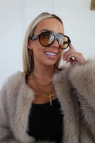 Woman wearing sunglasses and a fur coat with a white background
