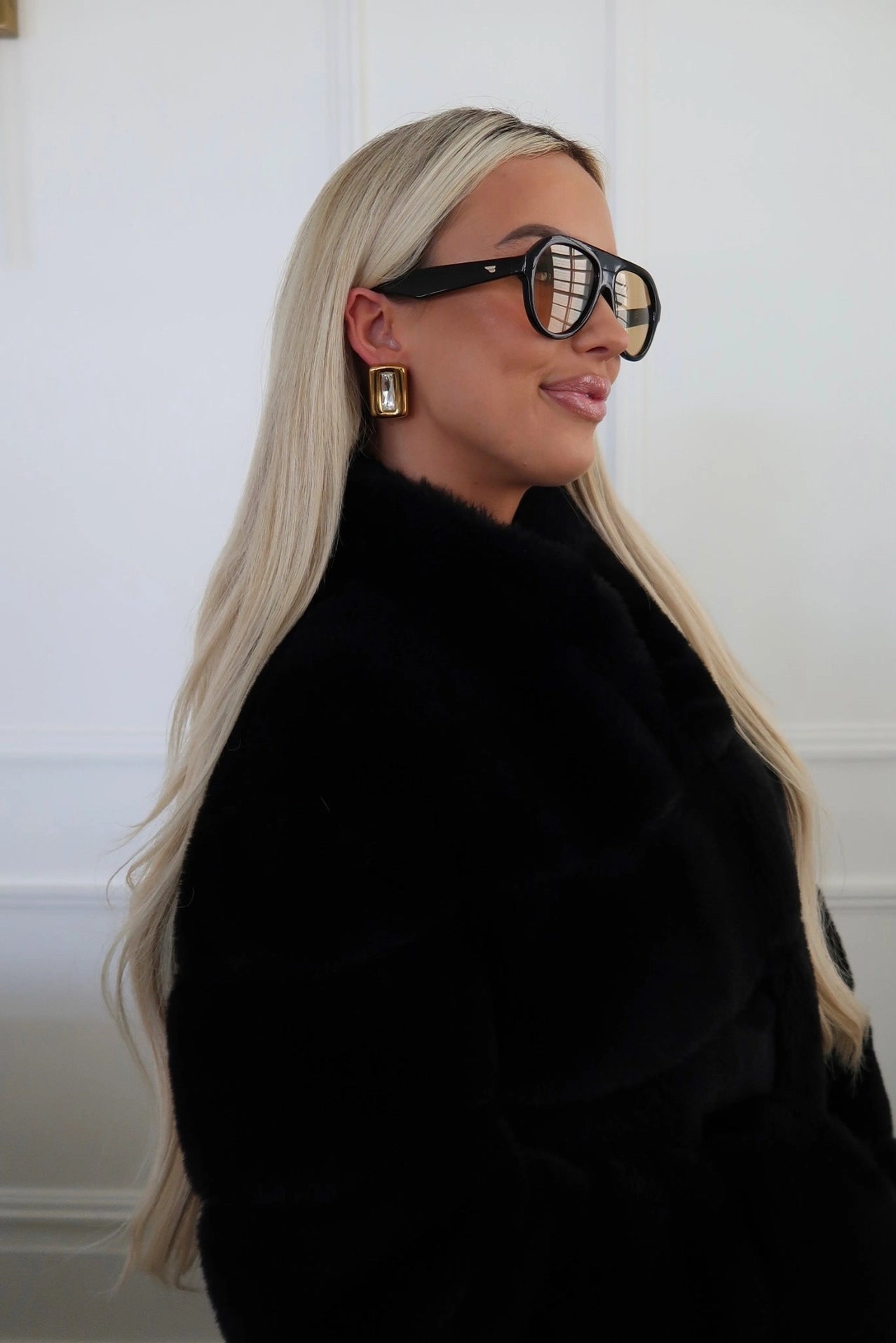 Person wearing a black outfit and sunglasses with a white background