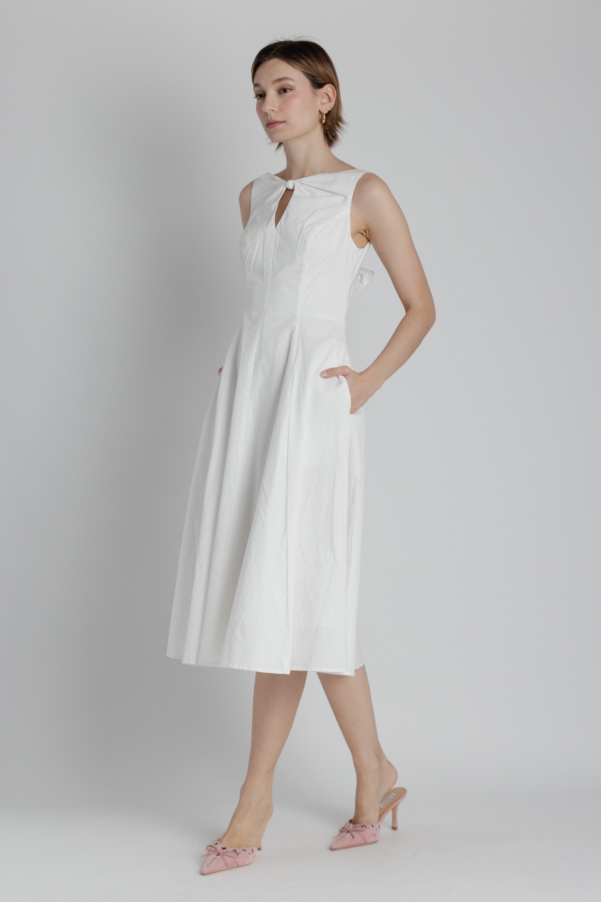 Woman wearing a white sleeveless dress on a plain background
